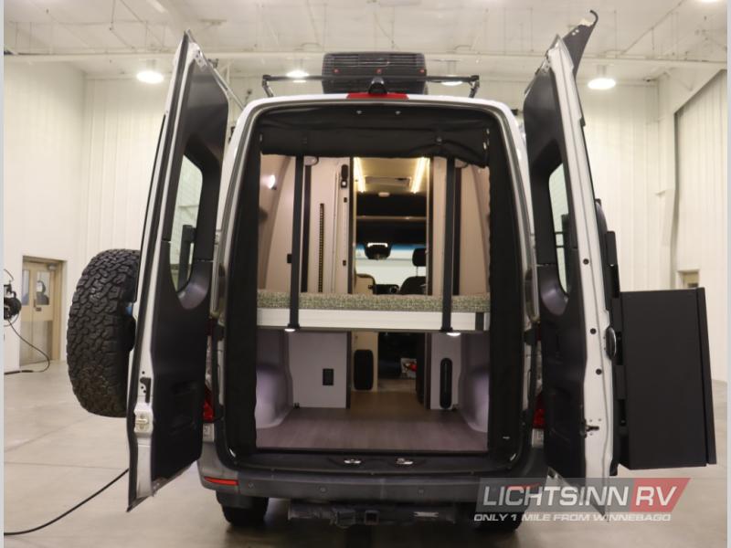  revealing a pull-out table and rear storage. Perfect for adventure.|Winnebago rv rental van with a rooftop AC unit — photo 5