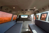 Inside a spacious RV rental campervan, featuring convertible beds & a view of a vast, golden field. Perfect for road trips!