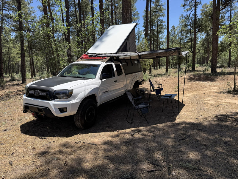 Overland-equipped Toyota Tacoma truck with pop-top camper & awning in a pine forest. Great for an rv rental adventure. — photo 13