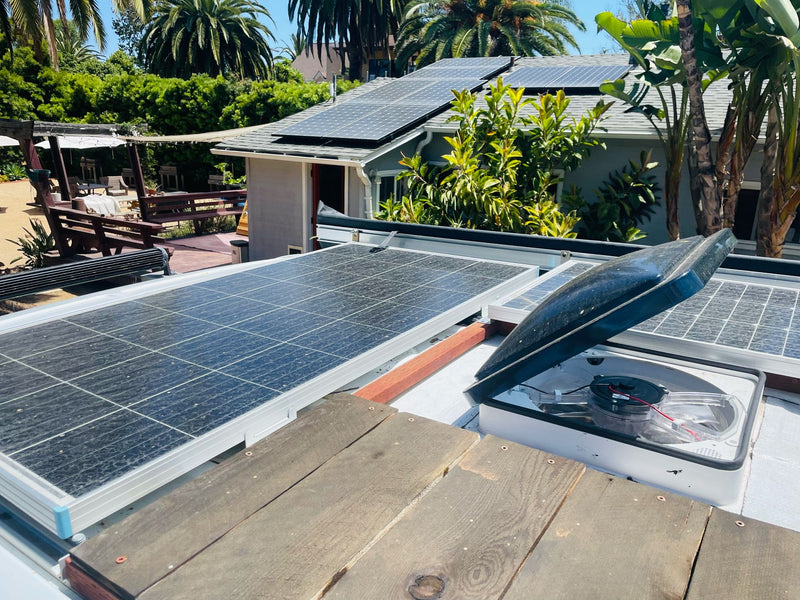 **RV rental** freedom! Solar panels & open vent fan on a camper van roof. Sunny outdoor setting with a house & garden. — photo 9