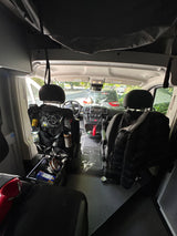 View into the front of an rv rental van, showcasing driver's area, passenger seat, and behind-seat organizers.
