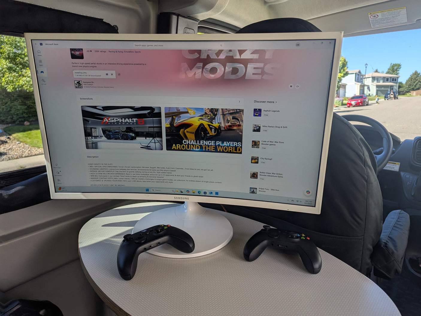 Inside an rv rental, a large monitor displays Asphalt 8 on Microsoft Store. Two Xbox controllers are ready for mobile gaming.