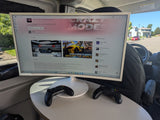 Inside an rv rental, a large monitor displays Asphalt 8 on Microsoft Store. Two Xbox controllers are ready for mobile gaming.