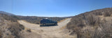 Dark SUV, ideal for an RV rental adventure, at a dirt road fork in dry hills.