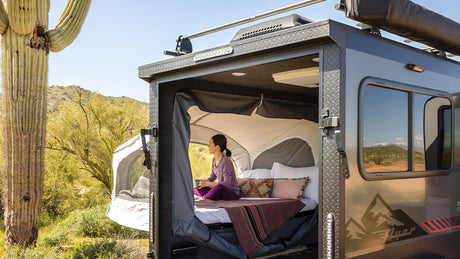 Enjoy desert views from a compact rv rental! A woman relaxes inside a cozy pop-up camper amidst saguaro cacti.