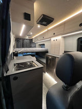 Bright and modern rv rental interior. Features strip lighting, integrated kitchen, controls, and storage.