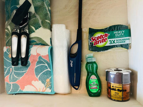 RV rental kitchen drawer: Sponges, dish soap, spices, lighter, bags, can opener, and towels organized.
