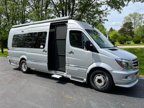 This silver Mercedes-Benz Sprinter Class B RV, available for rv rental, is parked with its passenger door open.