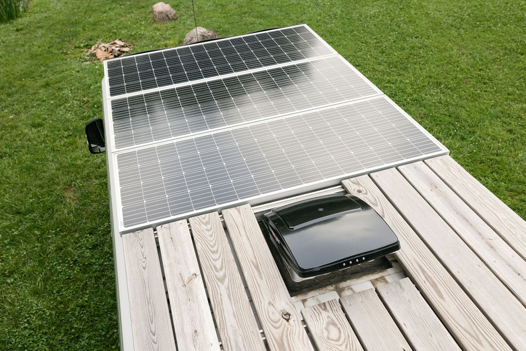 Overhead view of an RV roof, showcasing solar panels, a wooden deck, and a roof vent, ideal for an rv rental. — photo 4