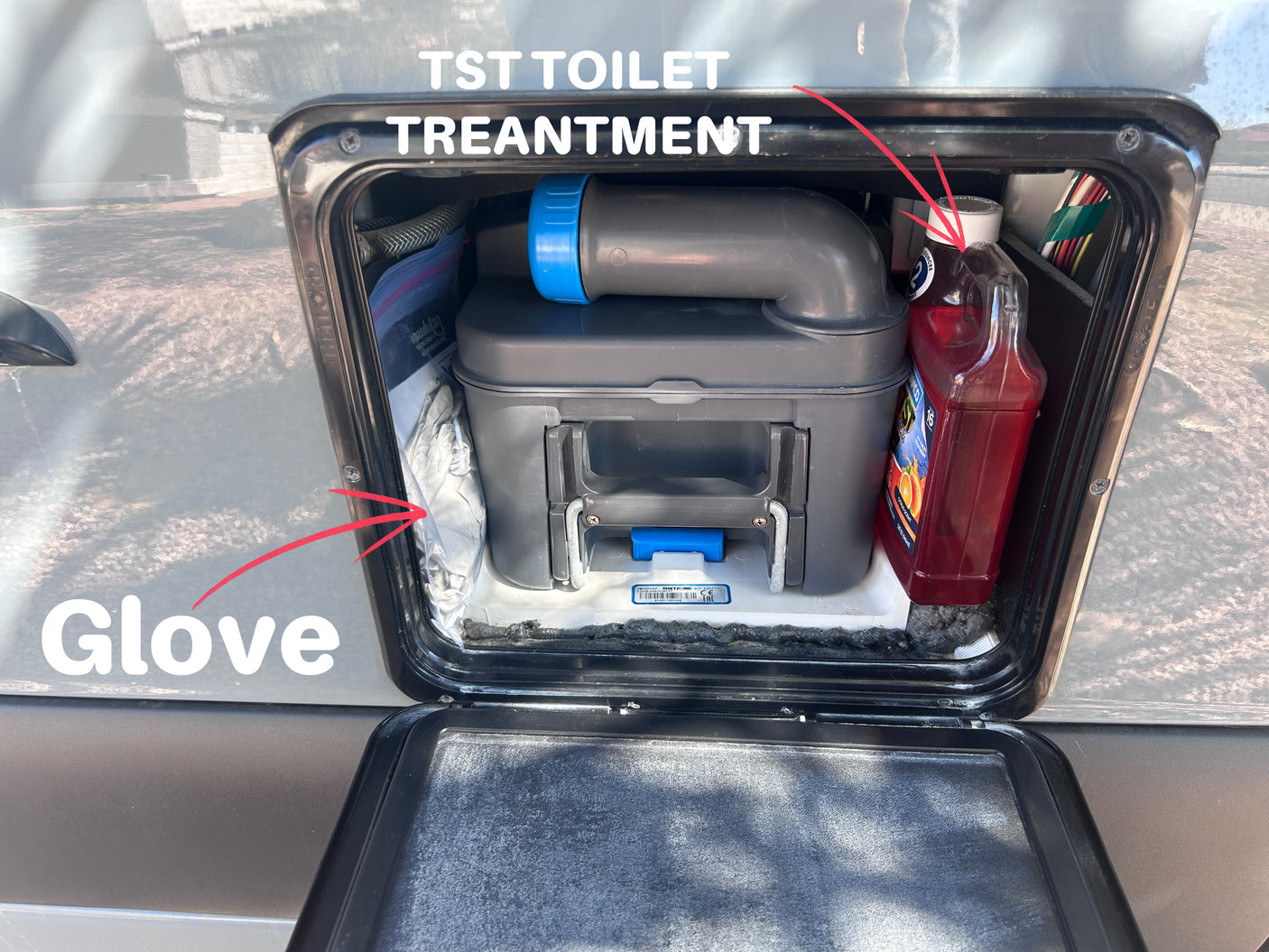 An rv rental's exterior compartment with a Thetford toilet cassette, TST treatment, and gloves for waste tank sanitation.