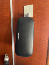 Stay entertained in your RV rental with this Bose portable speaker, conveniently hung on an adhesive hook on a wooden wall.