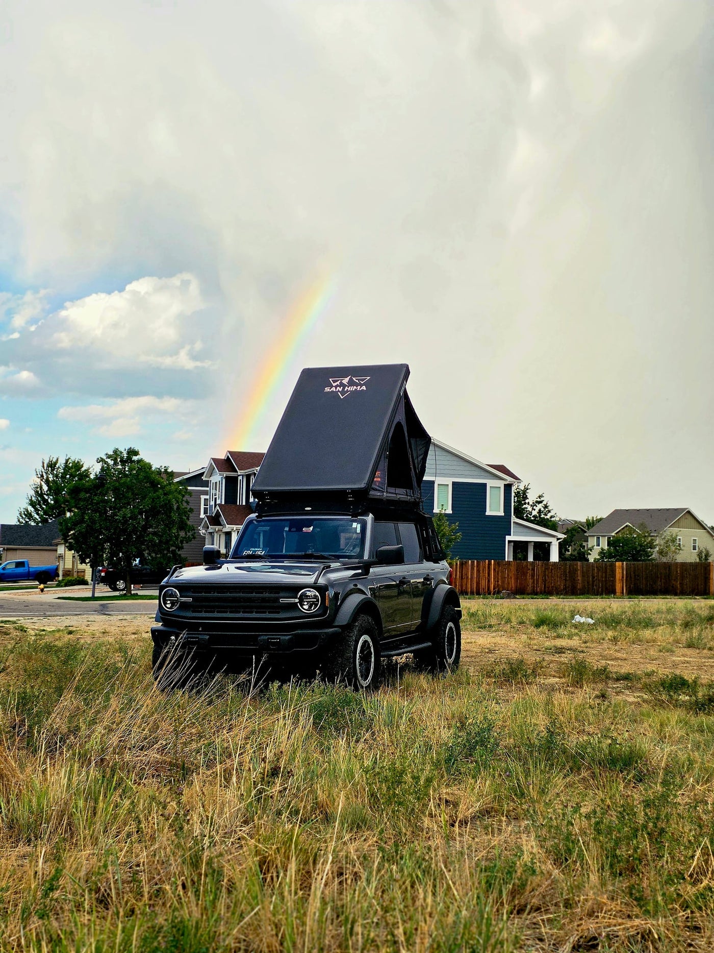  perfect as an RV rental for camping trips.|A dark gray Ford Bronco with an open rooftop tent in a grassy field — photo 8