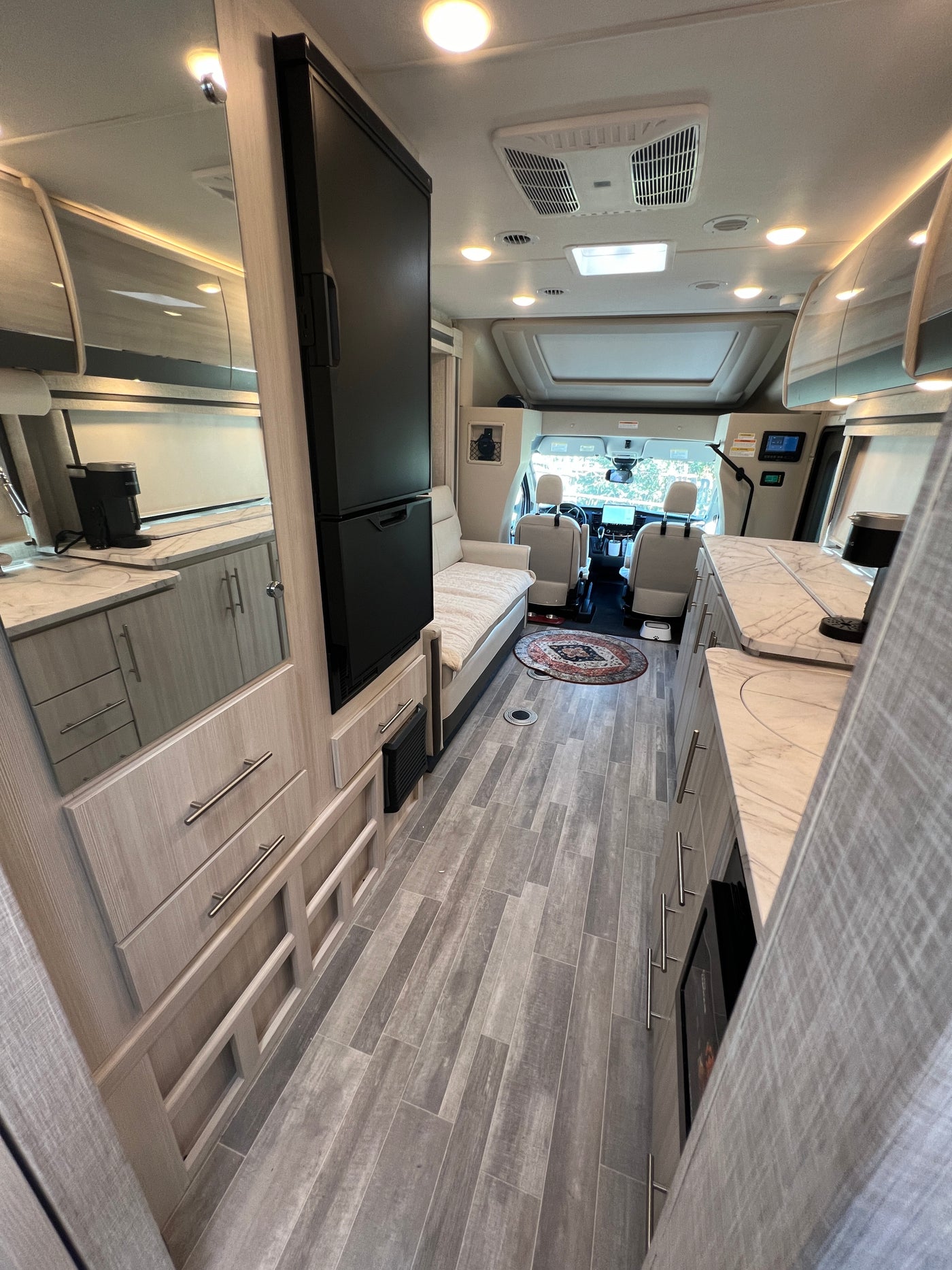 Modern and spacious rv rental interior, showcasing a full kitchenette, comfortable bench, and forward cockpit area. — photo 16