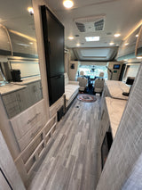 Modern and spacious rv rental interior, showcasing a full kitchenette, comfortable bench, and forward cockpit area.