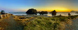 RV rental parked overlooking a panoramic sunset over a scenic coastline with sea stacks and a sandy beach.