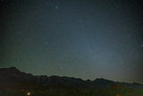 The dark night sky, filled with countless stars, stretches above silhouetted mountain ranges. Experience pristine nature on your RV rental adventure.