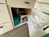 Smart under-sink storage for your RV rental: a blue bin, raccoon box, and clear bag holder optimize space.