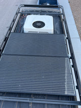Overhead shot of an RV rental's roof, showing efficient solar panels, an AC unit, and a robust roof rack system.