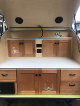 Compact RV rental galley with wooden cabinets, countertop, and fun decals, perfect for travel.
