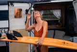 This RV rental makes outdoor showers easy! Happy surfer washes off by her van, board ready for the next wave.