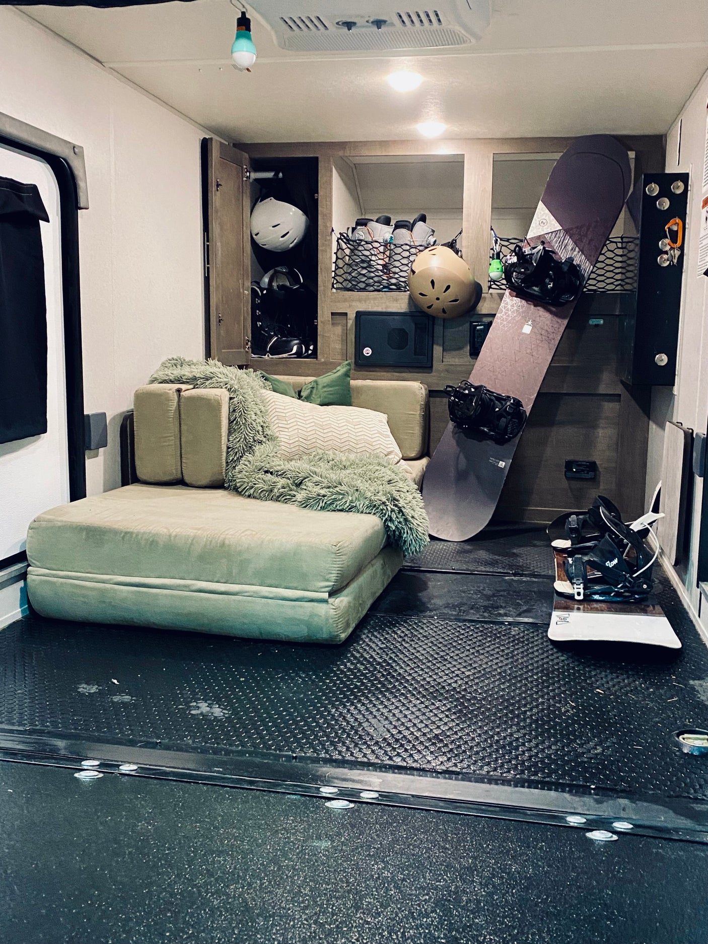 This cozy RV rental interior is set for snowboarding adventures, with gear storage, comfy seating, and two snowboards.