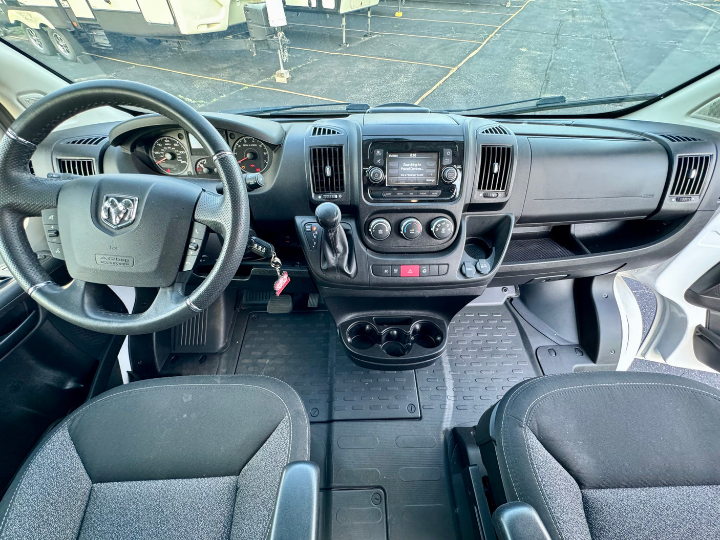 RV rental interior: driver's view of a modern dashboard, steering wheel, infotainment system, and front cabin amenities.