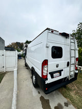 This white Ram Promaster RV rental, with rear ladder & roof rack, is ready for your next adventure.