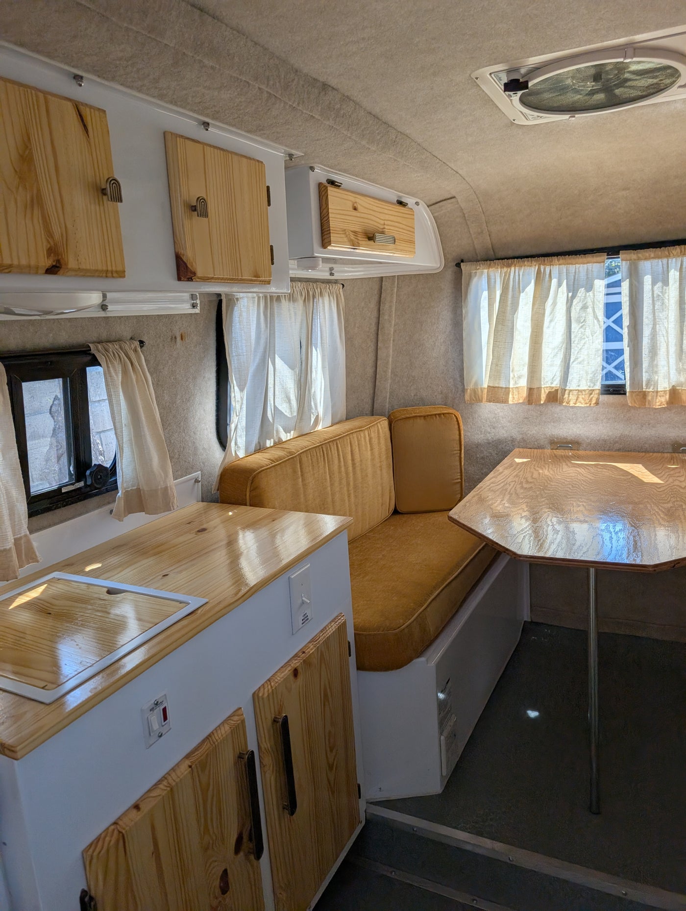 Step into this cozy RV rental's renovated interior, showcasing wooden cabinets, mustard cushions, and a compact kitchen. — photo 4