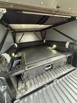Truck bed camper setup for RV rental: Organized storage with DECKED system, bright LED lights, and soft-shell canopy.