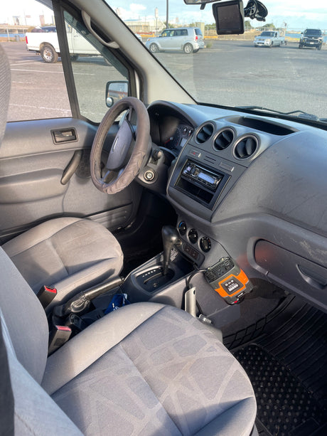 Inside an rv rental van: driver's side, dashboard, steering wheel, and a power inverter for on-the-go power needs.