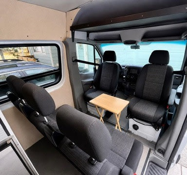  and an overhead bed platform.|This RV rental camper van conversion features a compact kitchen with stove and sink — photo 6