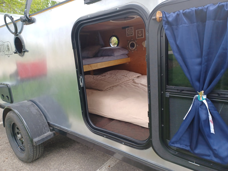 Inside a compact RV rental: a cozy sleeping area featuring bunk beds, nautical decor, and a porthole window. — photo 19