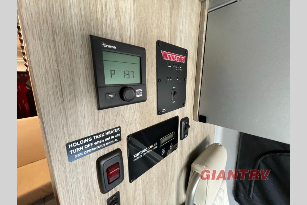 and overhead cabinets.|Off-white bench seat with zigzag patterns & seatbelts in an RV rental interior.|Modern RV rental interior: compact kitchen — photo 13
