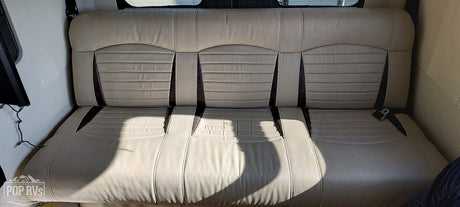 Modern RV rental interior showcasing a spacious, multi-section tan sofa with ribbed upholstery and seatbelts.
