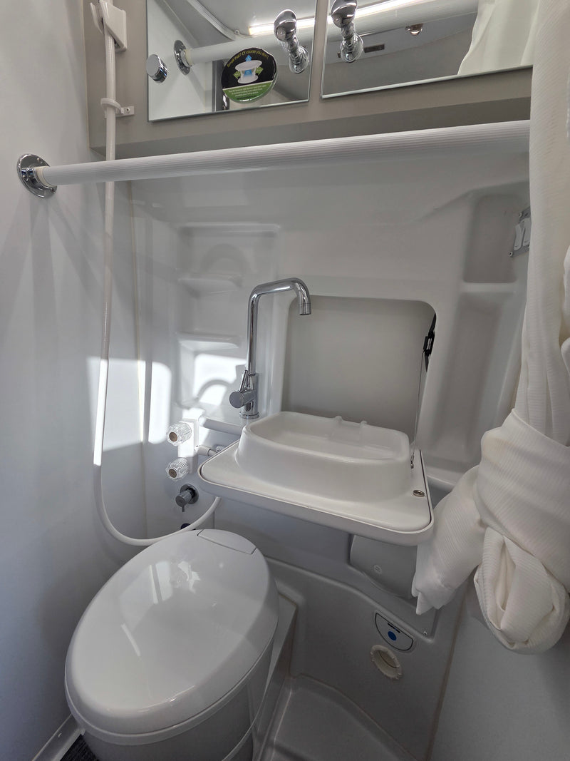 Compact RV rental wet bath featuring a toilet, foldable sink, and integrated shower for efficient space use. — photo 9