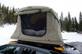Car with a deployed rooftop tent, an **RV rental** alternative, for winter camping in the snowy forest.
