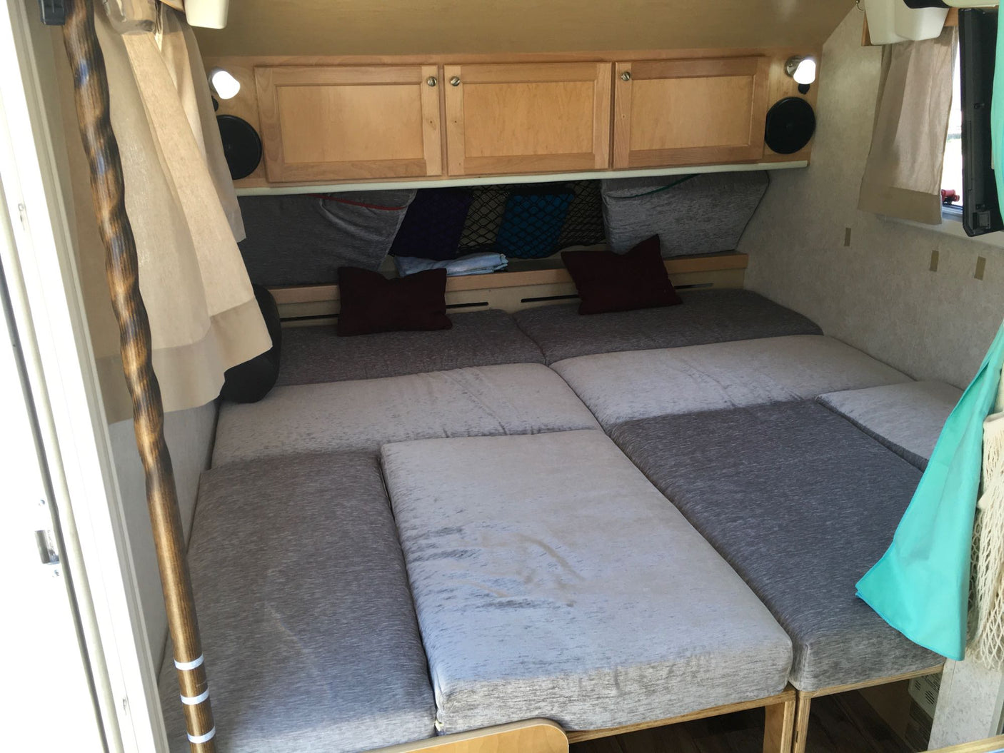 Cozy RV rental interior showcasing a modular bed, wood cabinets, and clever storage for compact living.