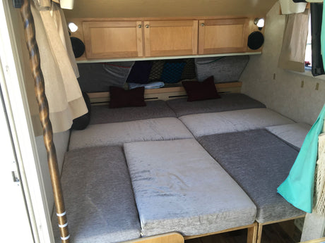Cozy RV rental interior showcasing a modular bed, wood cabinets, and clever storage for compact living.