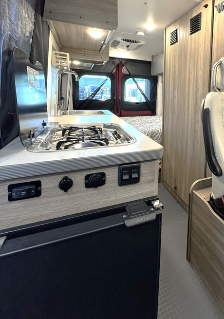 Inside this RV rental: compact kitchen with stove, sink, fridge. Bedroom, controls, and living space for your adventure.