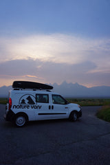 This Nature Vans rv rental van, with a Thule cargo box, is perfectly parked for a mountain sunset view.
