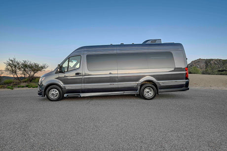 This sleek grey Sprinter camper van rv rental is parked in a scenic desert landscape, perfect for your next adventure.