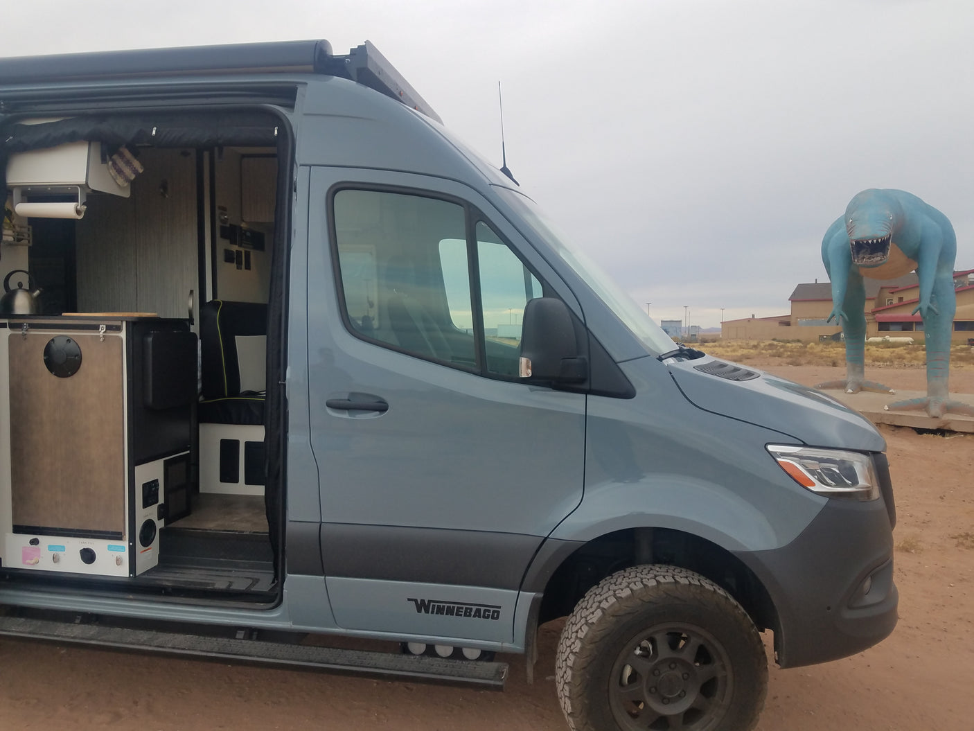 The interior of this Winnebago rv rental is ready for adventure, parked beside a huge blue dinosaur.