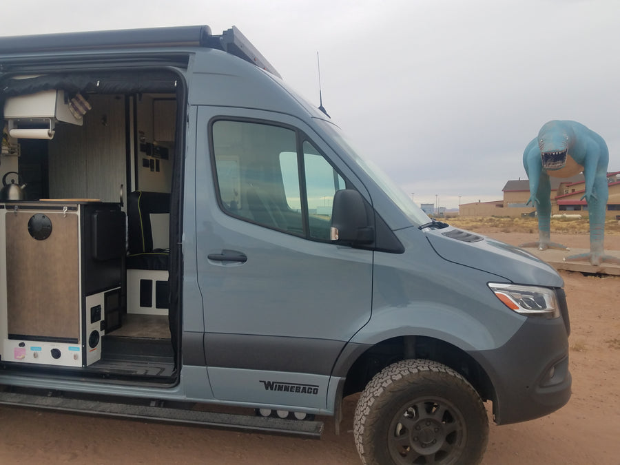 The interior of this Winnebago rv rental is ready for adventure, parked beside a huge blue dinosaur.