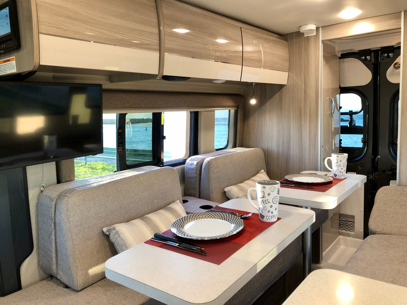 Cozy rv rental interior with a dining area for two, set tables, and a scenic water view outside the windows. — photo 6