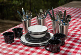 Essential outdoor dining gear: sturdy enamelware, mugs, and cutlery on a checkered tablecloth, ready for your RV rental adventure!