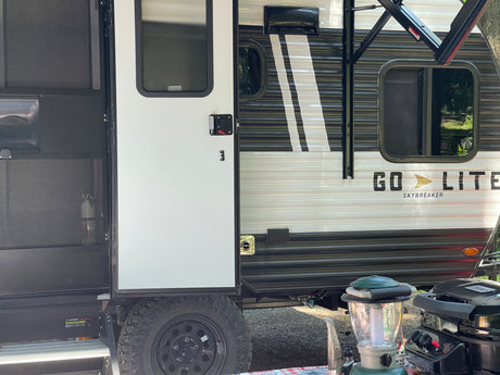 Go Lite Skybreaker RV rental ready for adventure. View shows the travel trailer's side, durable steps, and camping gear like a grill & lantern.