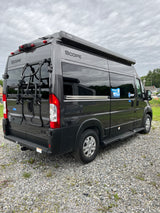 This dark grey Scope camper van, featuring a Thule awning and bike rack, is ready for your next rv rental road trip.