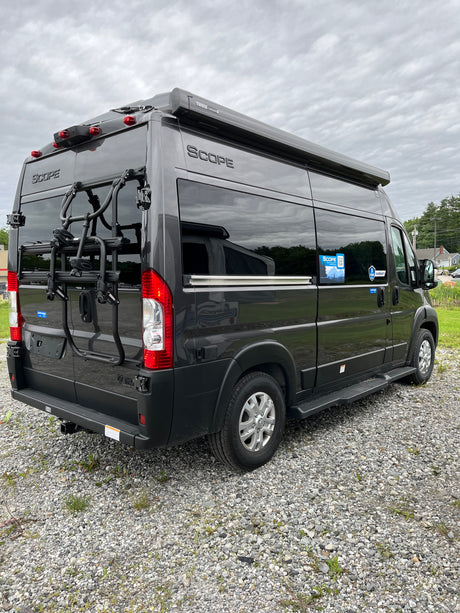 This dark grey Scope camper van, featuring a Thule awning and bike rack, is ready for your next rv rental road trip.