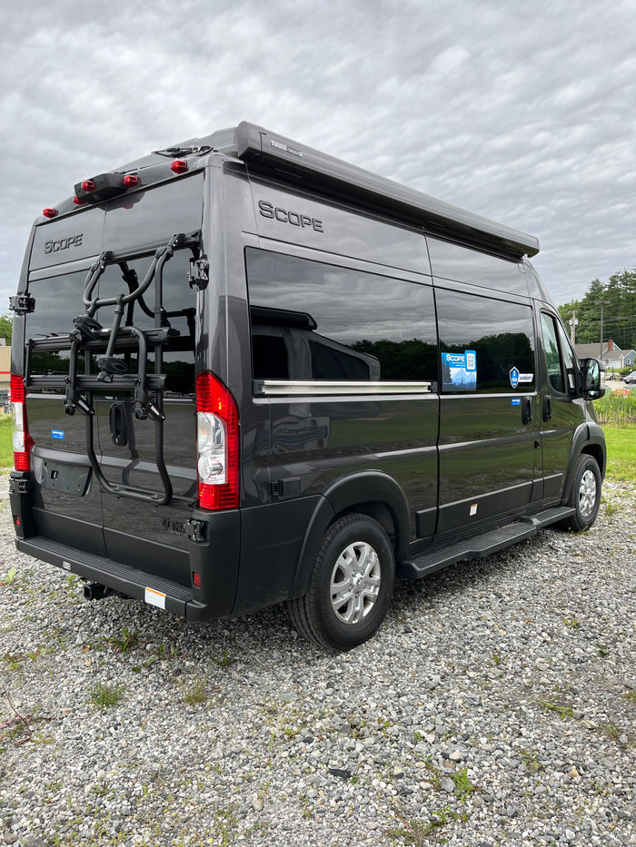 This dark grey Scope camper van, featuring a Thule awning and bike rack, is ready for your next rv rental road trip.