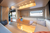 Modern rv rental interior: A bright, cozy dining area with a wooden table, bench seating, and a scenic window view.
